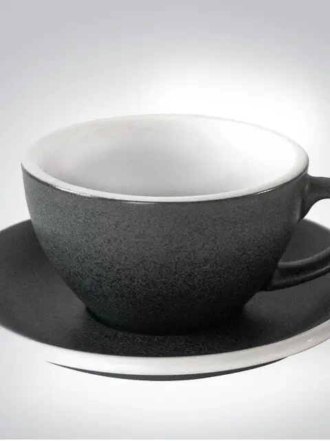 Schwarze Tasse mit Untertasse aus Keramik vor neutralem Hintergrund